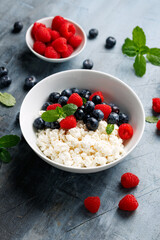 Bowl of cottage cheese, curd cheese with blueberry and raspberry. High protein healthy breakfast or lunch