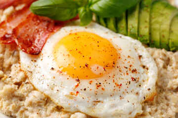 Savory Oatmeal breakfast with sunny side up fried egg, bacon and avocado. Healthy food