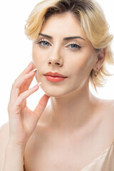 Fototapeta premium A young blonde girl with clear skin in a satin top. Beauty portrait of a woman on a white background in the studio.