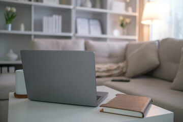 Close-up of a laptop on a table, complemented by a mug and a notebook, showcasing a stylish and relaxing home office vibe.