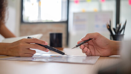 A detailed shot of two individuals reviewing and discussing a chart, representing collaboration and...