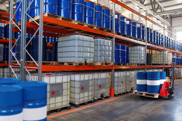 Chemical warehouse. Barrels with flammability symbol. Forklift in warehouse area. Oil barrels are...