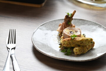 Close-up of a traditional spring dish – rabbit loin stuffed with a fragrant herb filling. The tender meat is sliced to reveal the delicious stuffing, highlighting the rustic yet elegant presentation. 