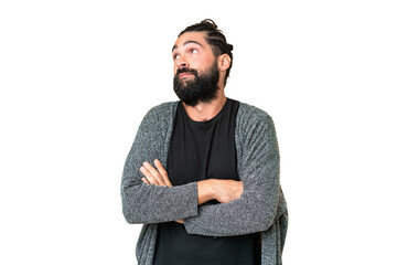 Young man with beard over isolated chroma key background making doubts gesture while lifting the...