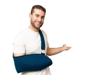 Young handsome blonde man with broken arm and wearing a sling over isolated chroma key background extending hands to the side for inviting to come
