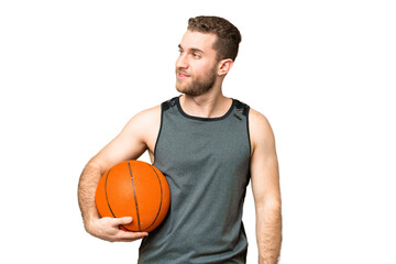Obraz premium Handsome young man playing basketball over isolated chroma key background looking to the side and smiling
