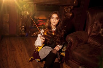 Fototapeta premium girl witch in glasses holds magic wand and magic book Cosplay