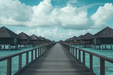 Obraz premium The long wooden bridge leads to the Maldives, with an endless sea and turquoise water. In front of it is a row of overwater bungalows. 