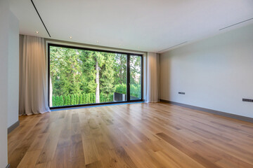 An empty room, unfurnished, with a panoramic view of the picturesque landscape on a summer day.