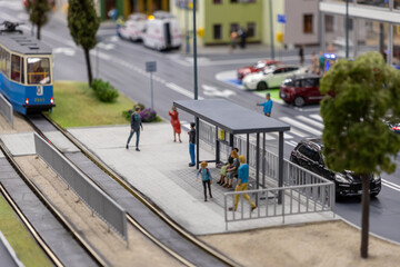 city tram stop with passengers, blue tram approaching, modern urban street design, and surrounding greenery