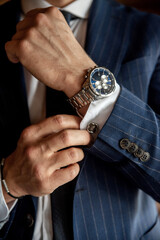White man checking cufflinks with wristwatch close up