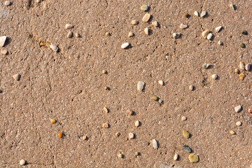 A close-up of a concrete surface reveals a scattering of small pebbles, creating a textured and slightly abstract background