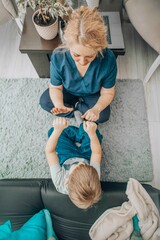 boy sitting on carpet with therapist mirroring hand movements, alternative learning in friendly...