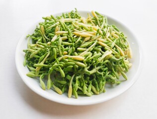 Uncooked papaya flower vegetables in a white plate on a white background. High angle view. 