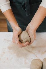 Fototapeta premium Girl potter is creating a ceramic ware in the workshop. Woman potter works with wet clay in the pottery studio.