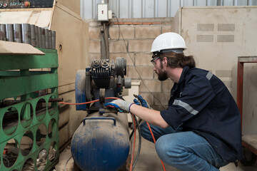 Professional male engineer worker working with air compressor in the industry factory. Male...