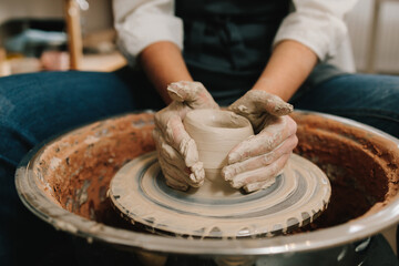 Process of sculpting ceramic crockery in the manufacturing. Female potter forms a clay product on a potter's wheel.