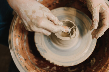 Molding earthenware with potters tools. Potter sculpts a ceramic mug from clay in the pottery studio.