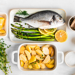 he concept of a delicious dinner. raw dorado fish with asparagus, lemon and potatoes