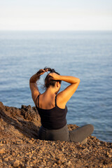 Chica arreglando el pelo en un acantilado sobre el mar