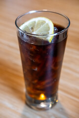 A glass of Cola with a slice of lemon on the table