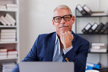 Fototapeta premium Businessman using laptop computer in office. Happy middle aged man, entrepreneur, small business owner working online.