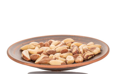Brazil nuts without shells in a clay plate, macro, isolated on white background.