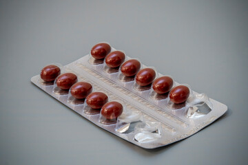 Bottles of brown capsules in a blister pack on a gray background