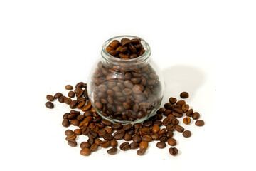 Freshly roasted coffee beans spilled from a glass jar on white background