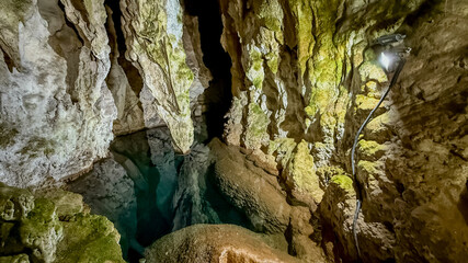 A breathtaking view of a natural cave's interior with stalactites and clear water, symbolizing exploration and adventure tourism  stopica pecina