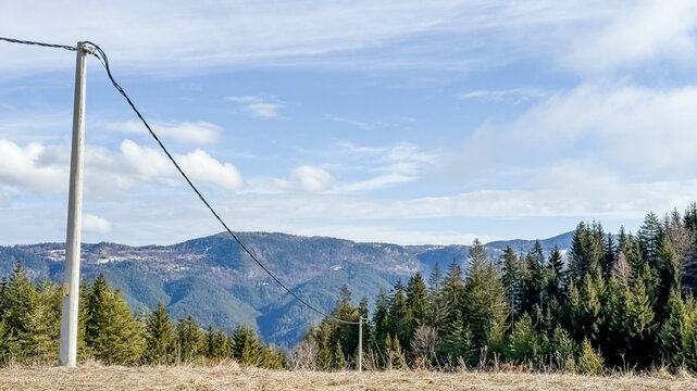 Scenic mountain view with power lines and evergreen forest, emphasizing rural infrastructure and environmental aesthetics, perfect for Earth Day