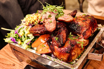 close up of Peruvian assorted grilled meat, including beef sirloin steak, baked sweet potato, salad, chicken, chorizo, sausages on a stove