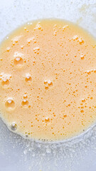 Close-up of frothy beaten eggs in a bowl for baking, highlighting the cooking preparation and breakfast concepts