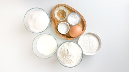A top-down view of baking ingredients in bowls, including flour, sugar, and an egg, ideal for holiday baking