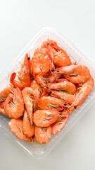 Fresh shrimp in a clear plastic container, perfect for seafood lovers, cooking inspiration, and summer barbecues