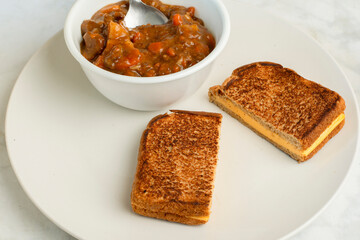 bowl of beef stew with  a cheese melt sandwich