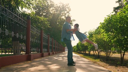 Child daughter walk with father dad spinning child on street. Carefree father daughter enjoying walk in park. Happy girl run to dad spinning in dad arms. Happy family. Child girl having fun with dad