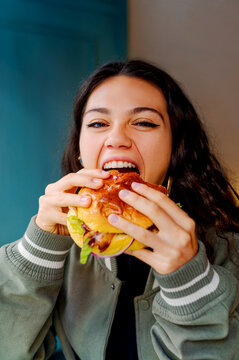 Young woman taking a big bite of a burger in a restaurant, enjoying her meal