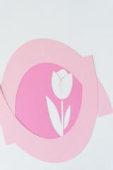 stencil with tulip flower shape machine-cut from pink paper and arranged with pink arcs on blank...