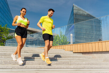 Young couple enjoying a morning jog down steps in an urban park on a sunny day