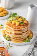 Pancakes with fruit and honey in plate on white background. Delicious dessert for Maslenitsa or Pancake Day. Healthy breakfast