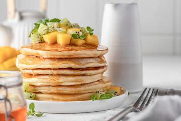 Pancakes with fruit and honey in plate on white background. Delicious dessert for Maslenitsa or Pancake Day. Healthy breakfast