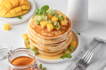 Pancakes with fruit and honey in plate on white background. Delicious dessert for Maslenitsa or Pancake Day. Healthy breakfast