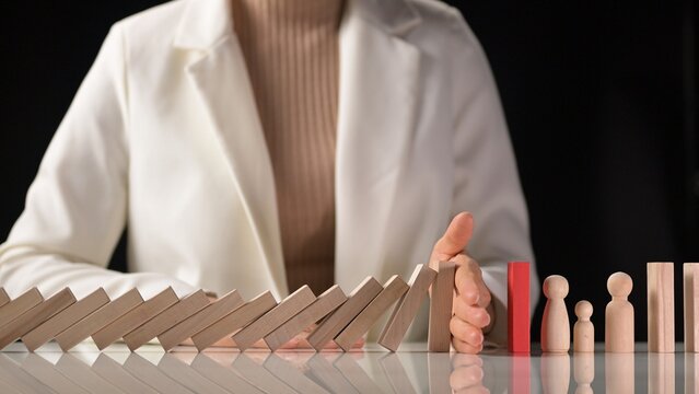 Mitigating business risks during a crisis strategic planning for growth and leadership in slow motion with hand stopping dominos falling enhancing decision making and risk management
