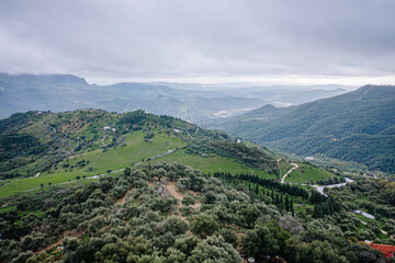A scenic view of Gaucín’s lush green hills and valleys under an overcast sky, showcasing the natural beauty of this Andalusian landscape.