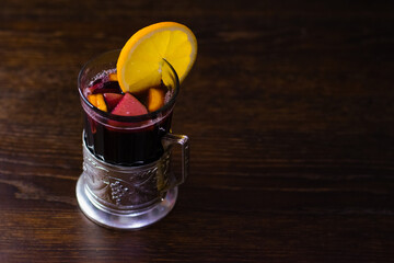 Delicious mulled wine with orange, cinnamon and honey in a glass with a vintage coaster on a dark...