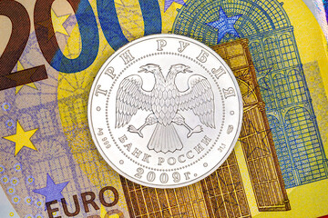 Silver coin three Russian rubles on the background of a paper banknote 200 euros. Money of the European Union