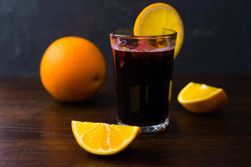 Delicious mulled wine with orange, cinnamon and honey in a glass on a dark background. Concept of a cozy winter evening, Christmas and New Year celebration
