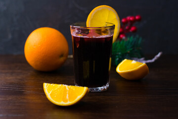 Delicious mulled wine with orange, cinnamon and honey in a glass on a dark background. Concept of a...