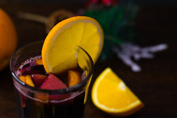 Delicious mulled wine with orange, cinnamon and honey in a glass on a dark background. Concept of a...
